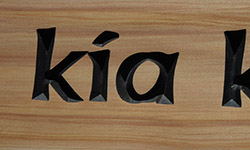 kia carved text close up on macrocarpa